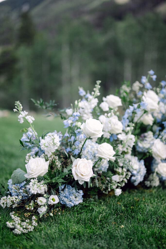 Elegant bridal bouquet featuring roses and trailing foliage, captured during a wedding in a natural, alpine landscape.